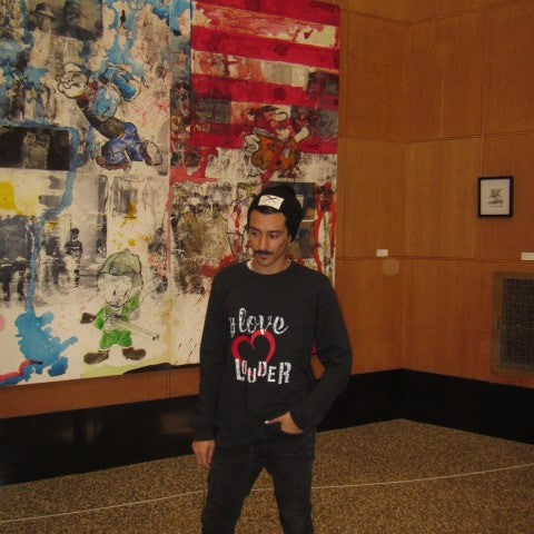 Man wearing black long sleeve tee shirt, hand-painted Love Louder in black with a large red heart centered on the front.