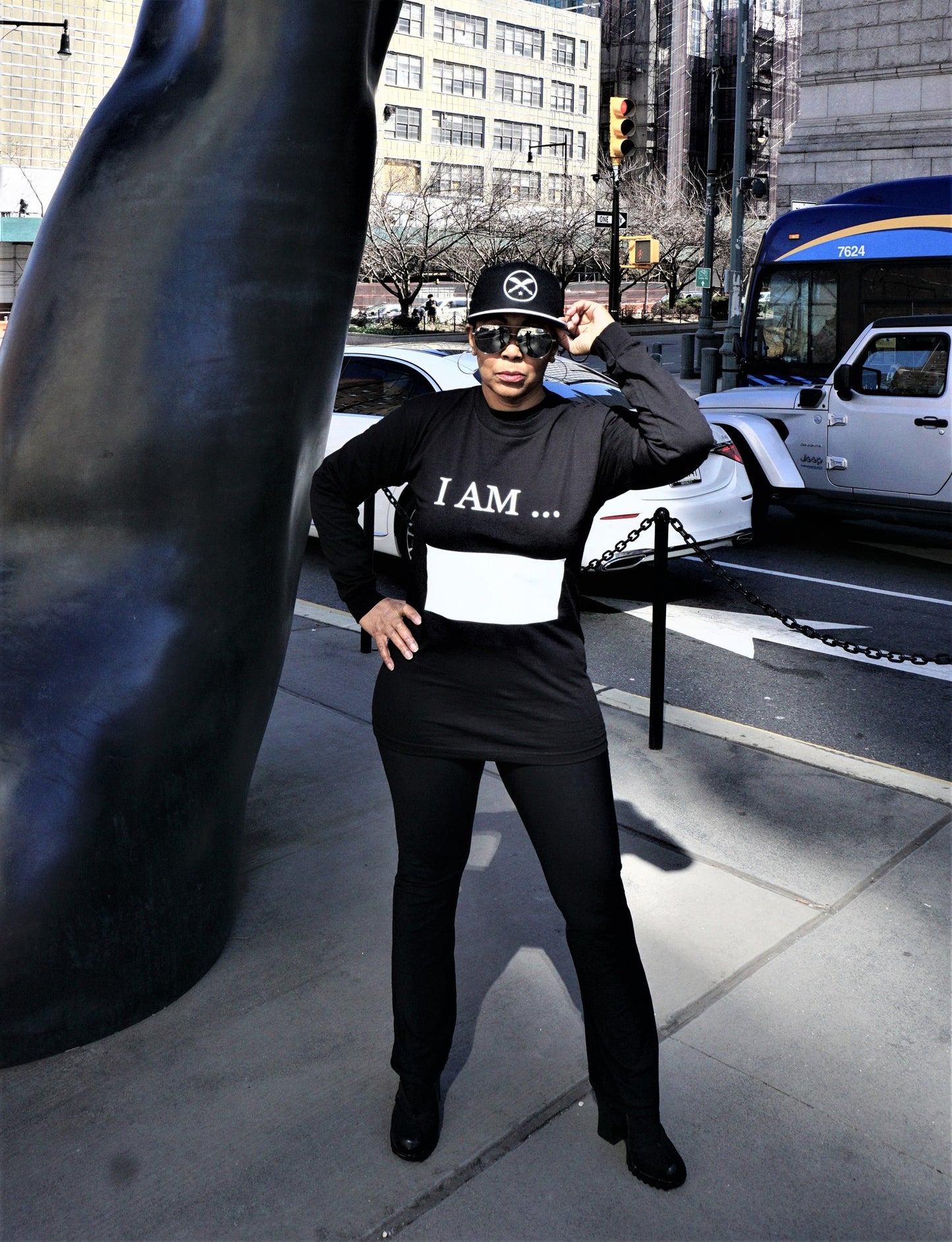 Women wearing long sleeve black Affirm tee shirt, with words I AM printed in white and large white writing block.