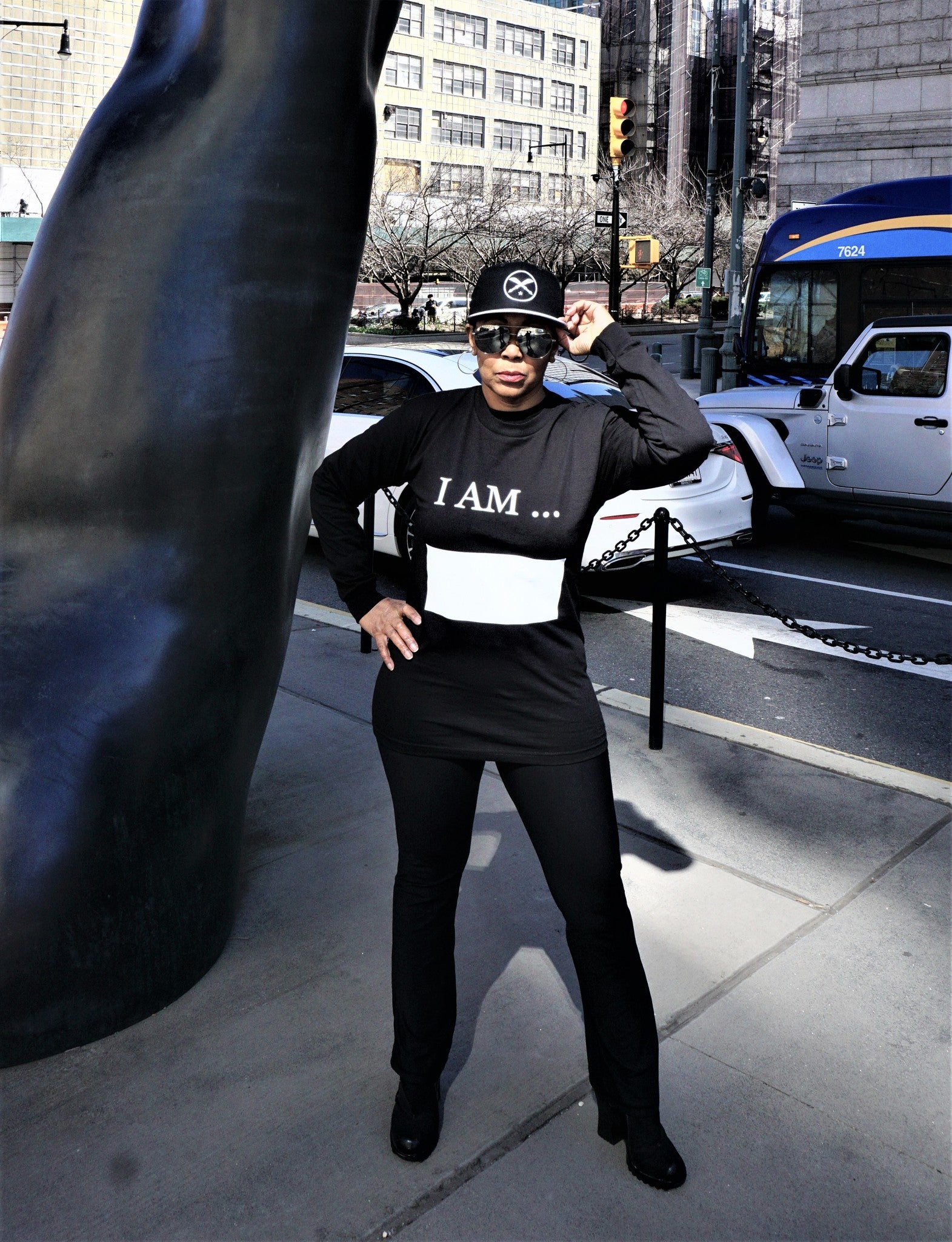Women wearing long sleeve black Affirm tee shirt, with words I AM printed in white and large white writing block.