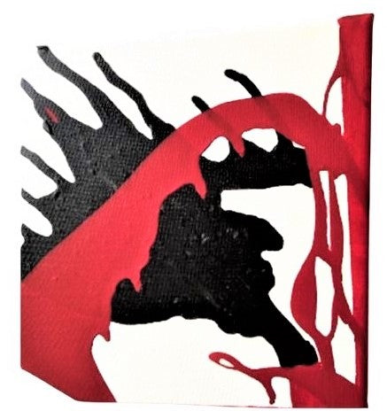 Close up view of textured abstract, white canvas piece featuring blown black paint with dripped red accents.