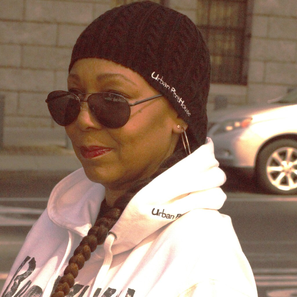 Woman wearing black fitted Cable Knit cap with Urban PentHouse embroidery in white.